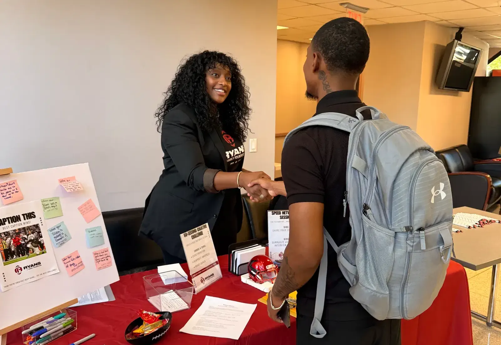 Ryans Family Foundation representative greeting a student with a backpack at an outreach table